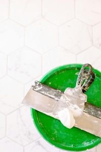 Close-up of a trowel and putty on a green bucket, ideal for renovation projects. Gros plan d'une truelle et d'un enduit sur un seau vert, idéal pour les projets de rénovation.