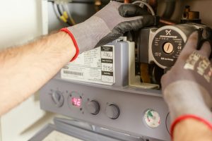 Close-up of hands adjusting a boiler system with precise instrumentation, showing maintenance work. Gros plan des mains ajustant un système de chaudière avec une instrumentation précise, montrant des travaux de maintenance.
