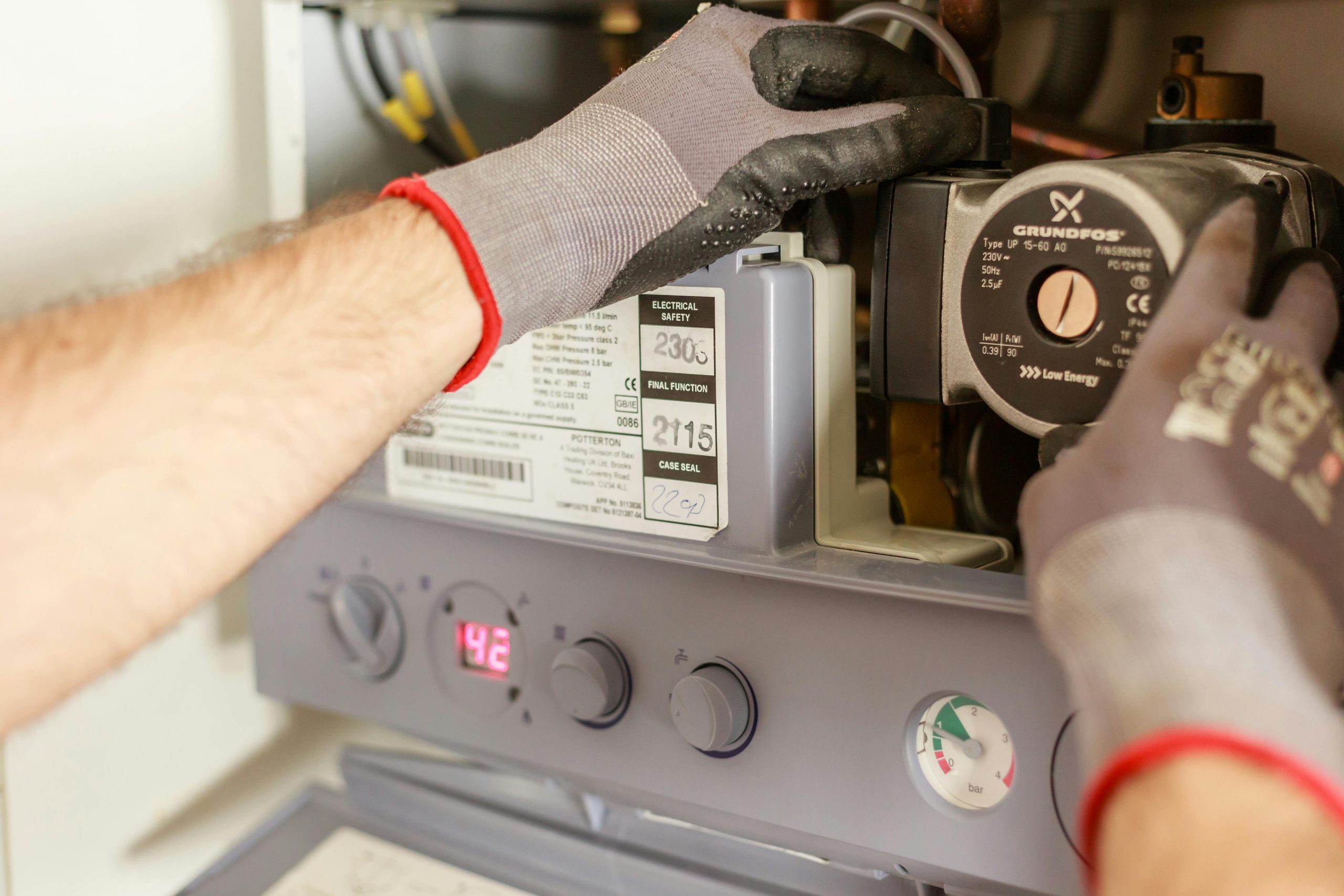 Close-up of hands adjusting a boiler system with precise instrumentation, showing maintenance work. Gros plan des mains ajustant un système de chaudière avec une instrumentation précise, montrant des travaux de maintenance.