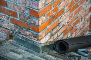Detailed view of a brick chimney featuring construction tools and materials for repair. Vue détaillée d'une cheminée en briques présentant des outils de construction et des matériaux de réparation.