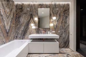 Interior design of modern bathroom with mirror hanging on wall above sink and big bathroom and illuminated with round lamps Design intérieur d'une salle de bain moderne avec miroir accroché au mur au-dessus du lavabo et grande salle de bain illuminée par des lampes rondes