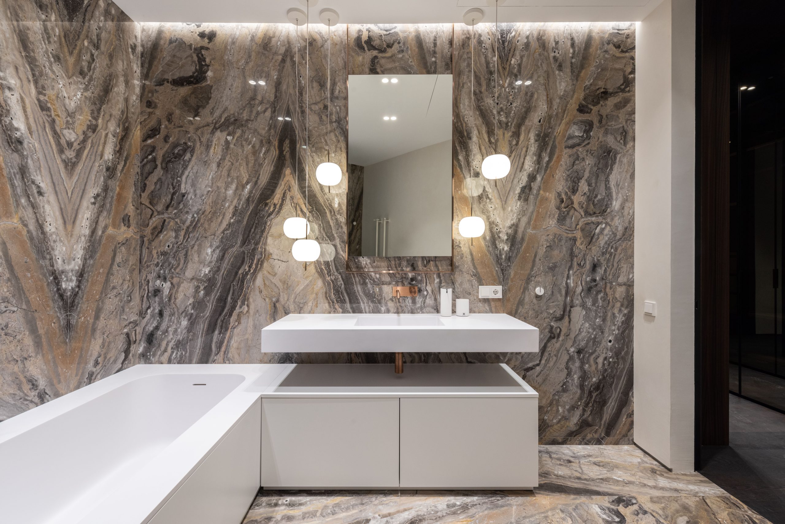 Interior design of modern bathroom with mirror hanging on wall above sink and big bathroom and illuminated with round lamps Design intérieur d'une salle de bain moderne avec miroir accroché au mur au-dessus du lavabo et grande salle de bain illuminée par des lampes rondes
