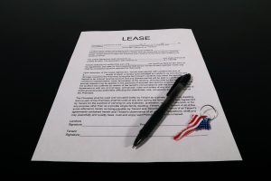Lease agreement document with pen and American flag keychain on a black table. Document d'accord de location avec stylo et porte-clés drapeau américain sur une table noire.