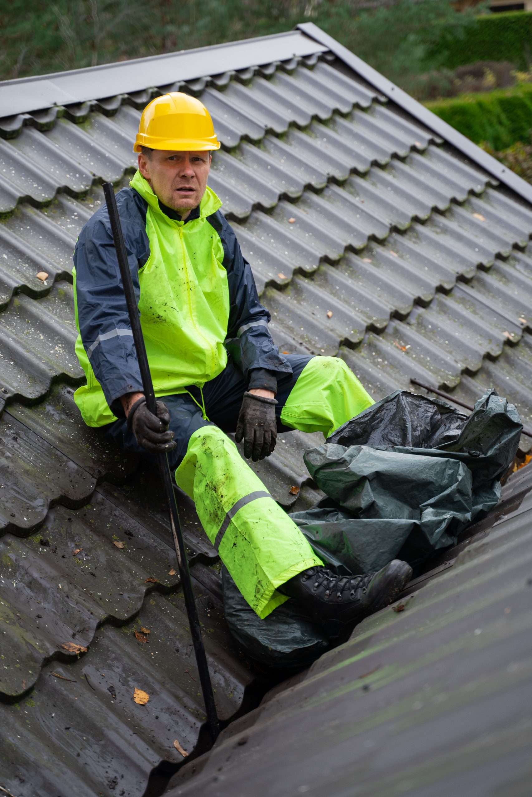A construction worker in safety gear performing roof maintenance outdoors. Un ouvrier du bâtiment en équipement de sécurité effectuant l'entretien du toit en extérieur.