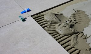 Close-up of wet cement and tile spacers during floor tile installation. Gros plan sur du ciment humide et des espaceurs de carrelage lors de l'installation de carreaux de sol.