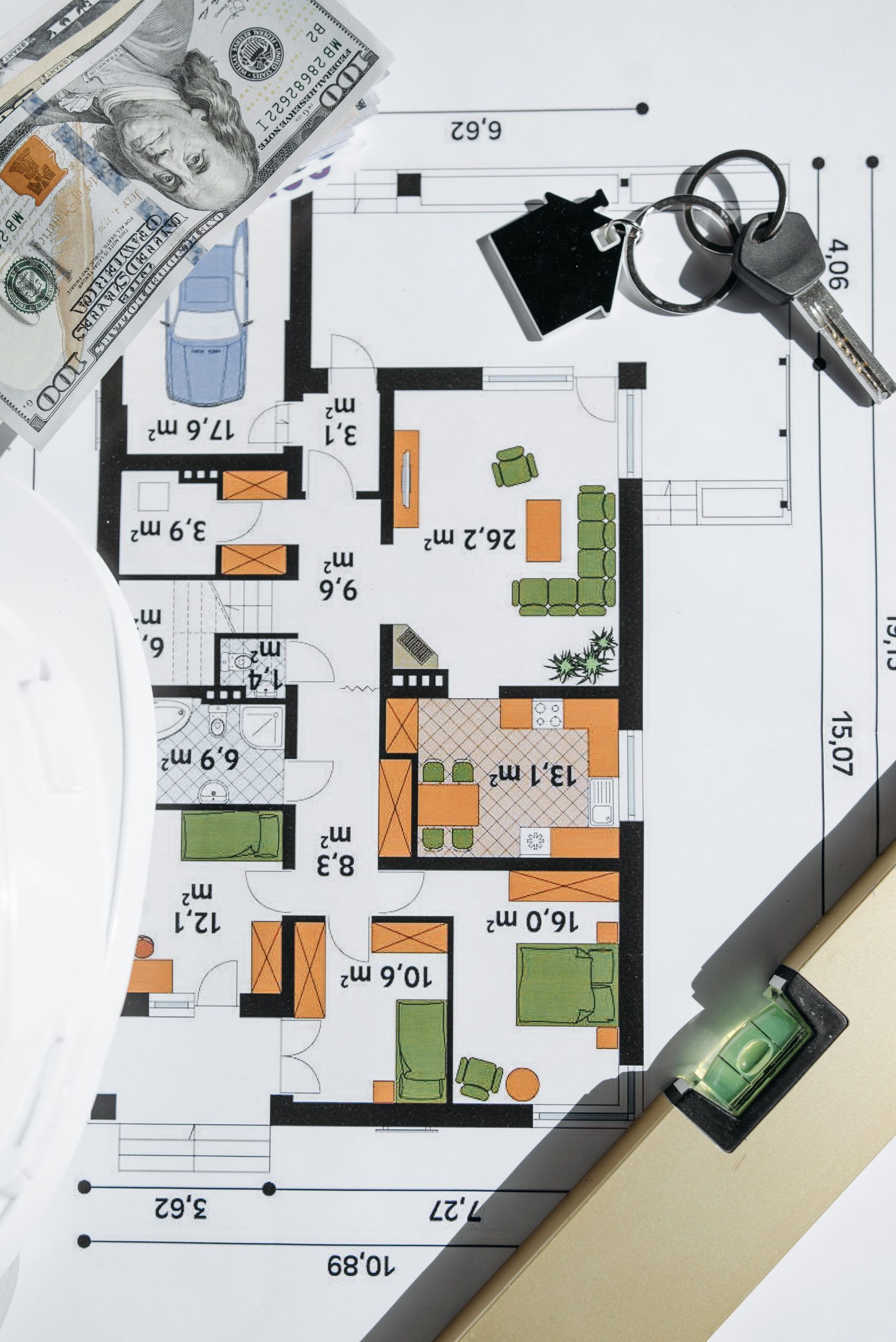 Vue aérienne d'un plan d'étage d'une maison avec des clés et de l'argent, symbolisant l'investissement immobilier.
