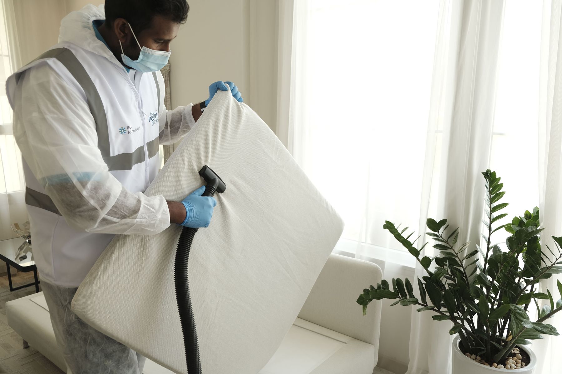 Technicien qui aspire un matelas avec un aspirateur