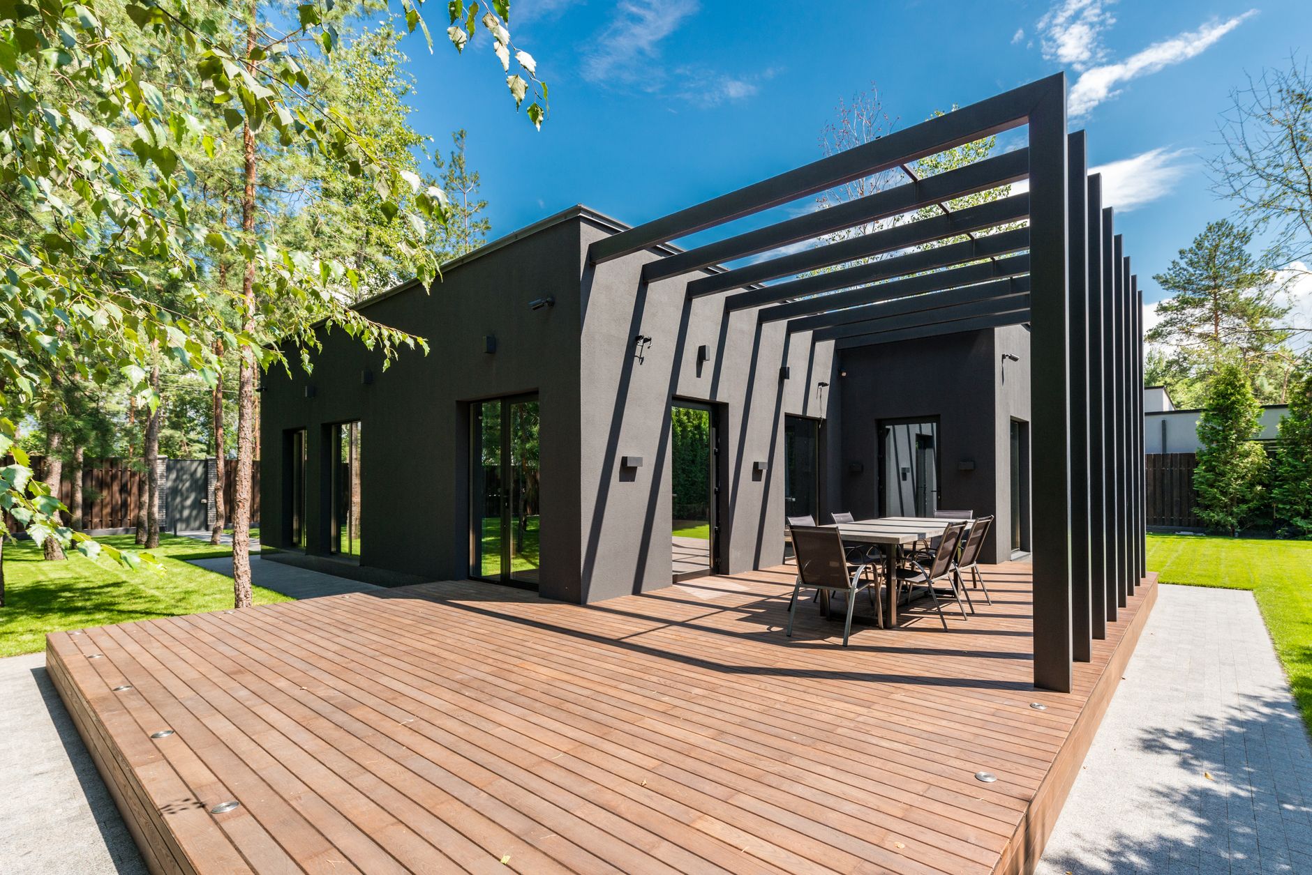 Terrasse en bois avec table à manger entourée de verdure