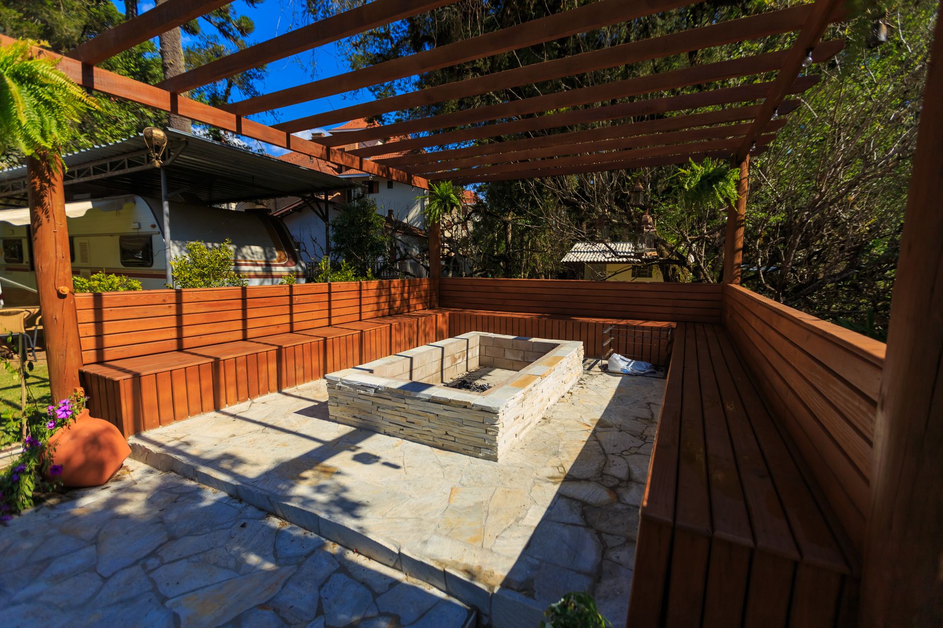 Terrasse avec foyer en pierre et bancs sous une pergola